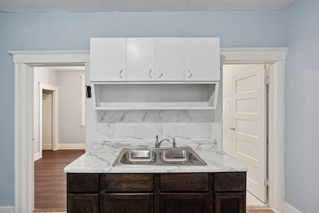 kitchen with hardwood / wood-style floors, light stone counters, white cabinetry, and sink