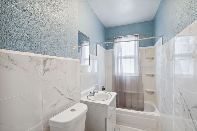 full bathroom with vanity, toilet, tile walls, and tiled shower / bath combo