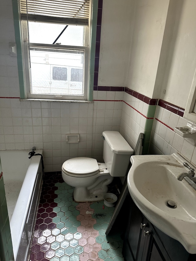 bathroom with vanity, toilet, tile walls, and a tub