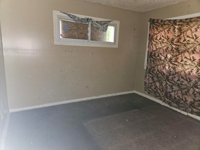 spare room featuring dark colored carpet and a textured ceiling