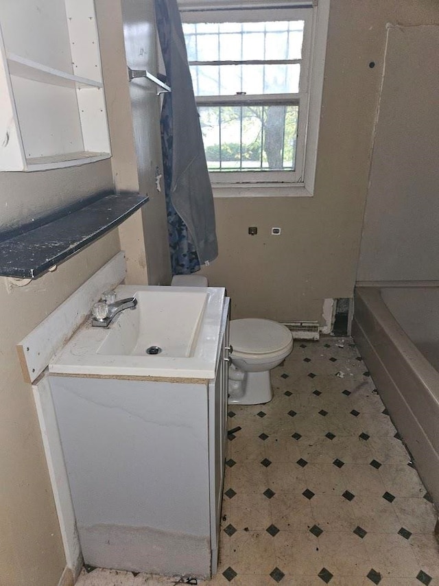 bathroom with a tub to relax in, vanity, and toilet