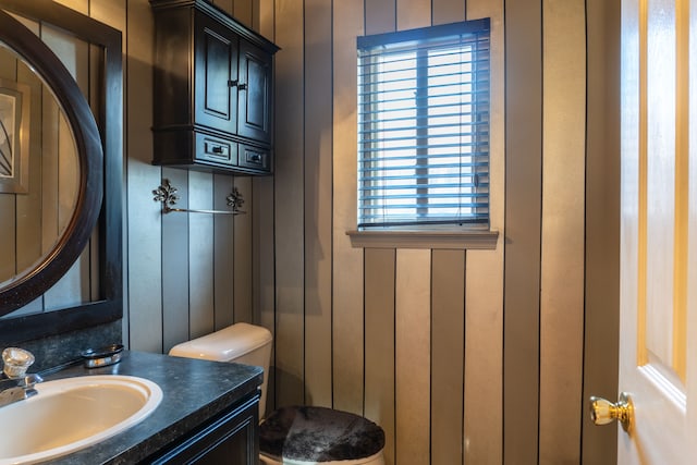 bathroom with wooden walls, vanity, and toilet