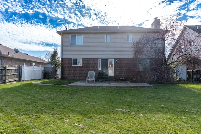 rear view of property featuring a yard, a patio, and a shed