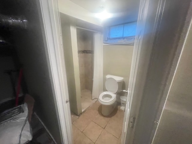 bathroom with a shower, tile patterned flooring, and toilet