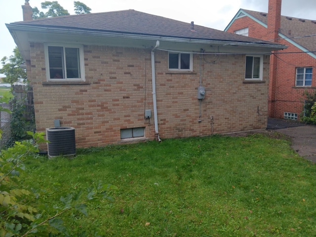 back of house with central air condition unit and a yard