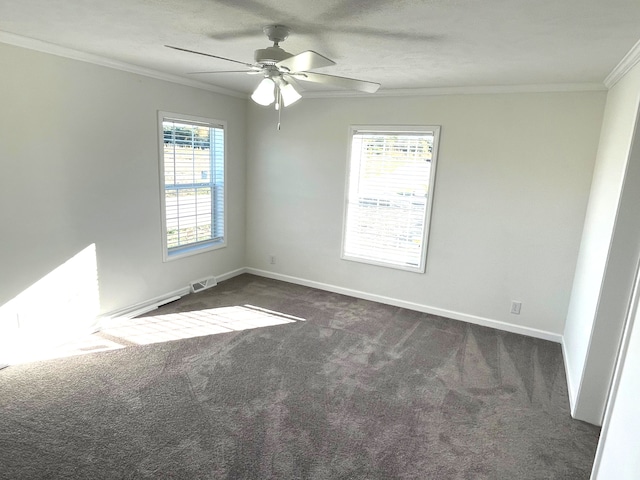 spare room featuring a wealth of natural light, crown molding, ceiling fan, and dark colored carpet