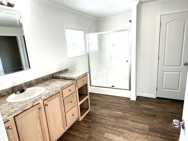 bathroom with hardwood / wood-style floors, vanity, a shower with shower door, and ornamental molding