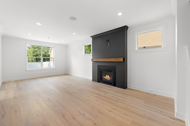 unfurnished living room with a large fireplace and light wood-type flooring