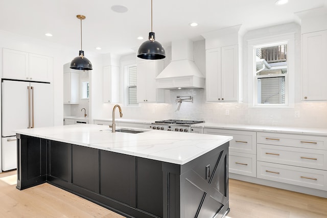 kitchen with custom exhaust hood, sink, decorative light fixtures, white cabinets, and a large island