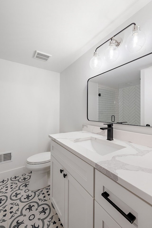 bathroom with tile patterned floors, vanity, toilet, and a shower with door