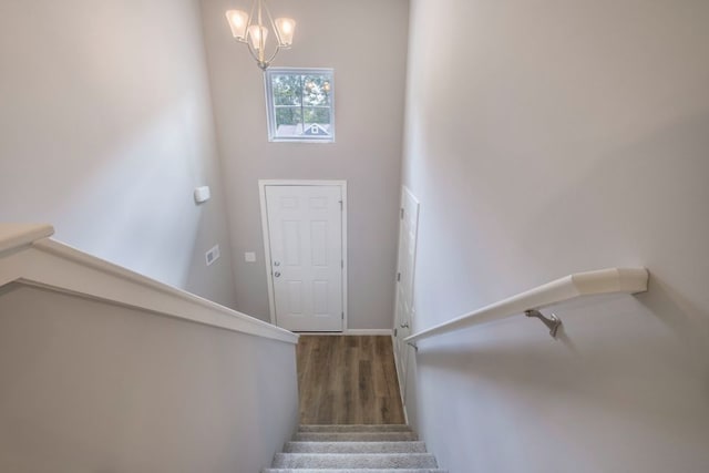 staircase with an inviting chandelier and hardwood / wood-style flooring