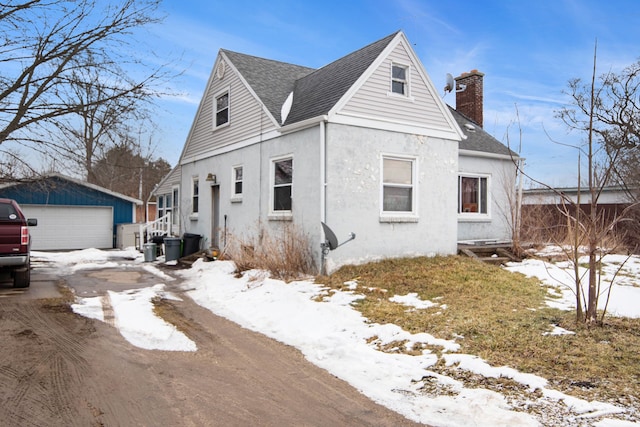 6000 N Dort Hwy, Flint, MI 48505 - view of front of house featuring a chimney, a shingled roof, an outdoor structure, stucco siding, and a garage