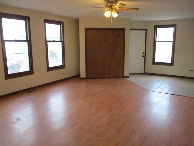 empty room featuring plenty of natural light, ceiling fan, and light wood-type flooring