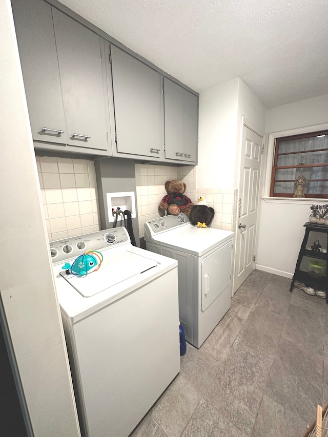 laundry room featuring cabinets, a textured ceiling, and washing machine and dryer