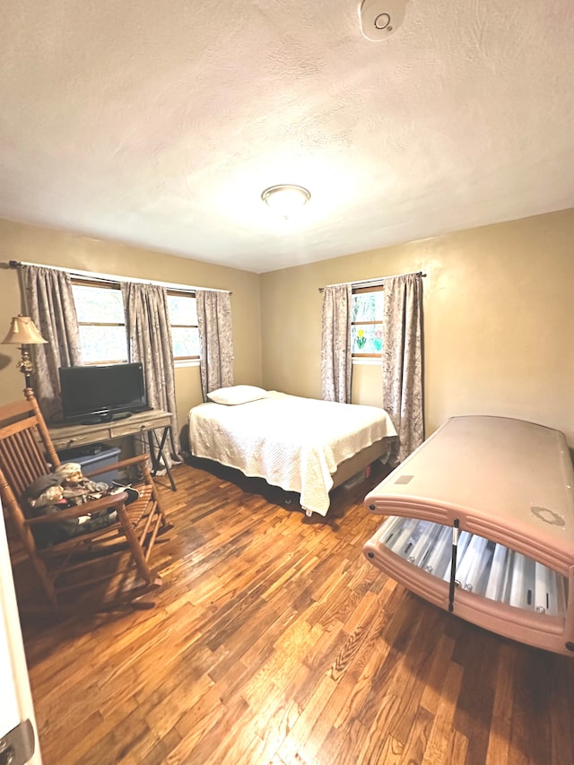 bedroom featuring wood-type flooring, a textured ceiling, and multiple windows