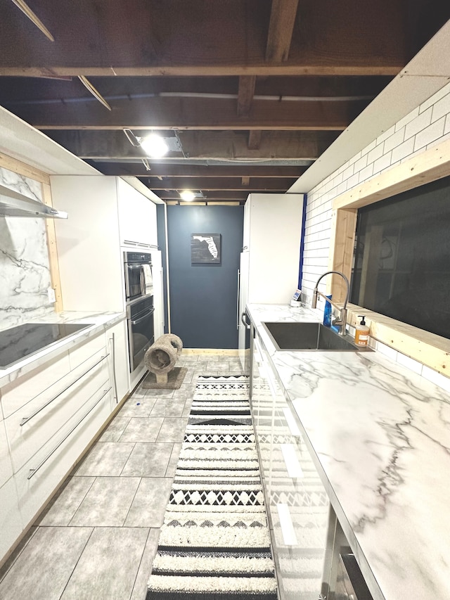 kitchen featuring white cabinets, sink, light tile patterned floors, double oven, and cooktop