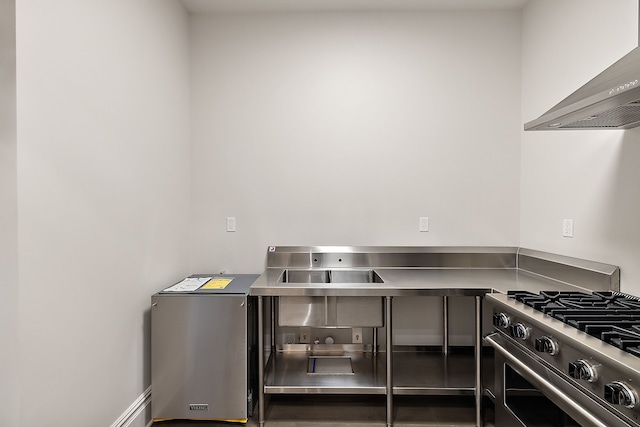 kitchen with stainless steel counters, wall chimney range hood, and stainless steel appliances