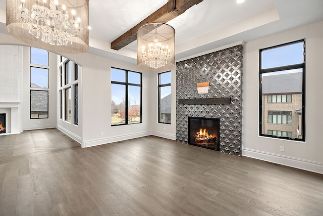 unfurnished living room with beamed ceiling, a large fireplace, dark wood-type flooring, and a healthy amount of sunlight