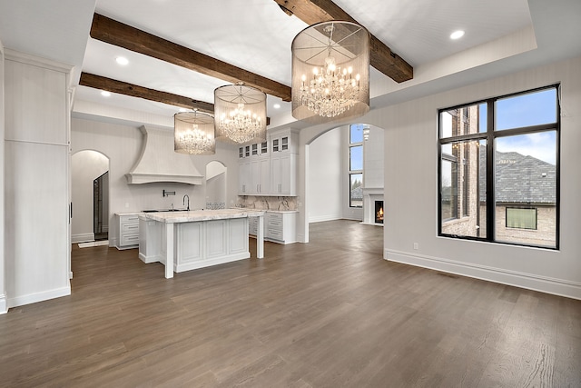 kitchen featuring pendant lighting, a center island, dark hardwood / wood-style flooring, a kitchen bar, and white cabinetry