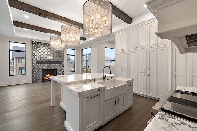 kitchen featuring plenty of natural light, a kitchen island with sink, sink, decorative light fixtures, and a tiled fireplace