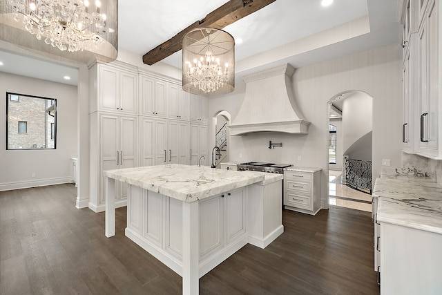 kitchen with decorative light fixtures, white cabinetry, a kitchen island with sink, and custom exhaust hood