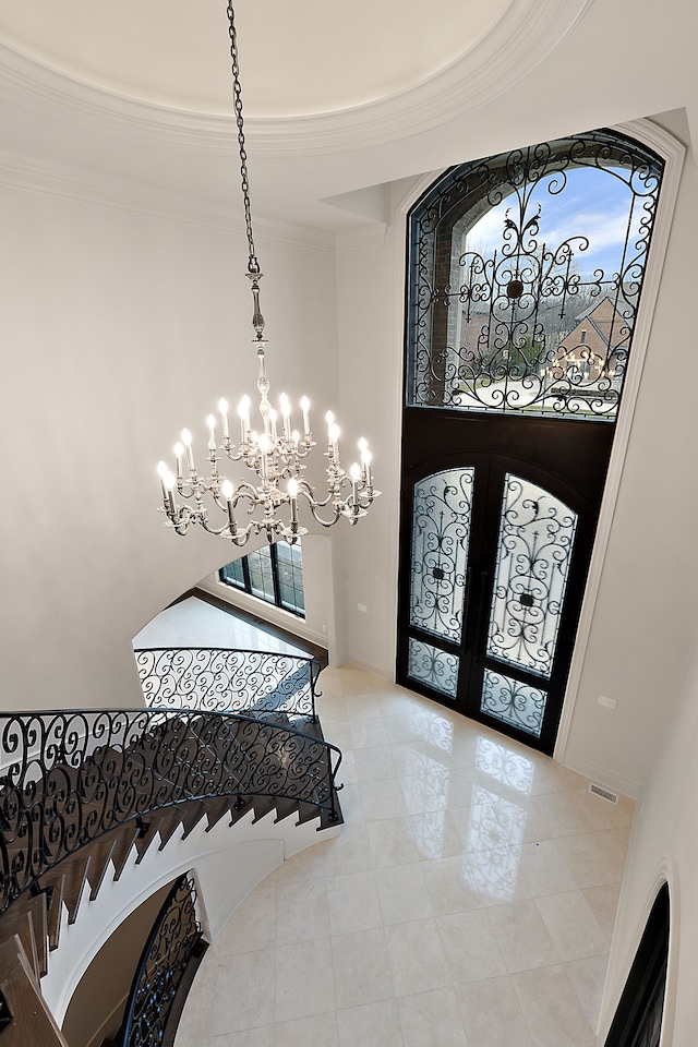 foyer with a chandelier, french doors, and ornamental molding