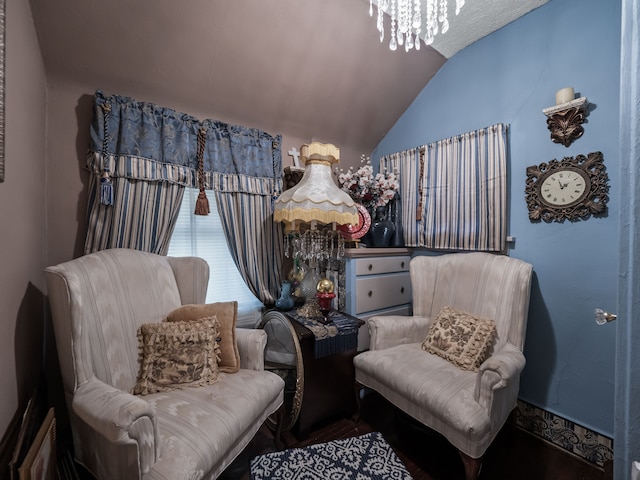 sitting room with vaulted ceiling and an inviting chandelier