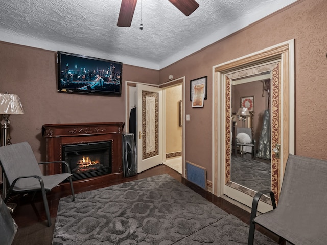 living area featuring ceiling fan, dark hardwood / wood-style flooring, and a textured ceiling