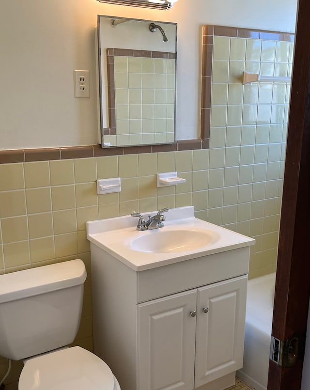 bathroom with vanity, a tub to relax in, toilet, and tile walls