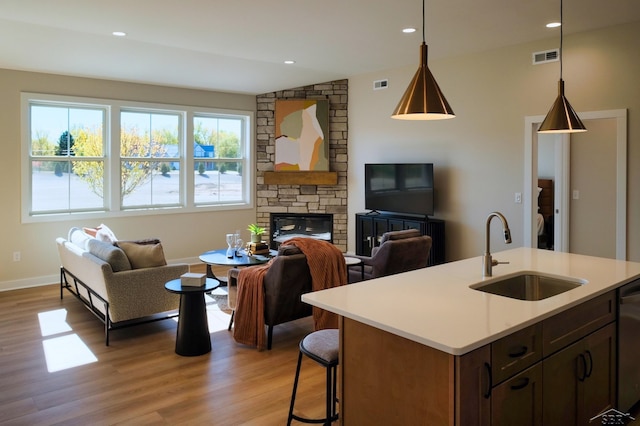 kitchen with light wood-type flooring, vaulted ceiling, hanging light fixtures, and sink