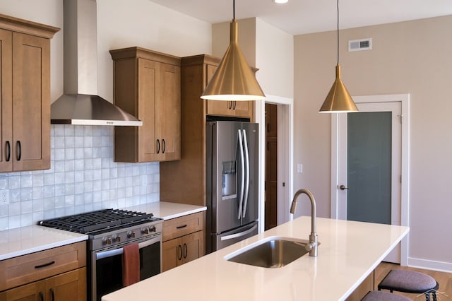 kitchen featuring sink, wall chimney exhaust hood, hanging light fixtures, stainless steel appliances, and backsplash