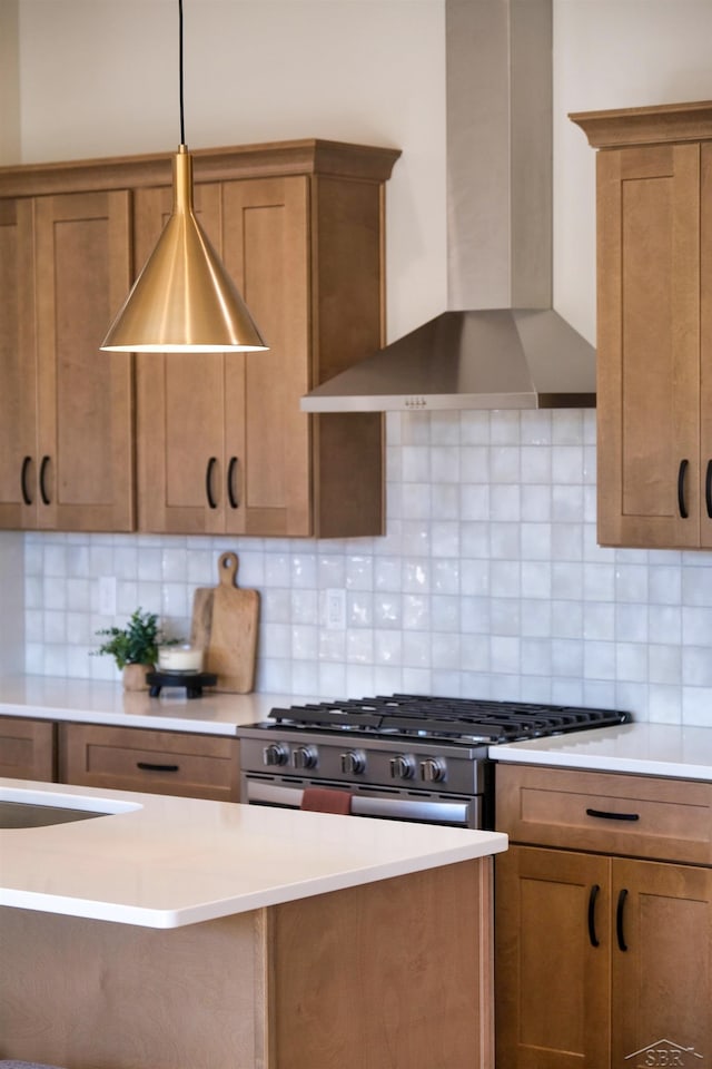 kitchen featuring high end stove, tasteful backsplash, hanging light fixtures, and wall chimney range hood