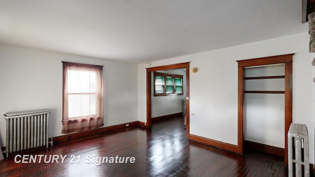 spare room featuring radiator heating unit and dark hardwood / wood-style floors