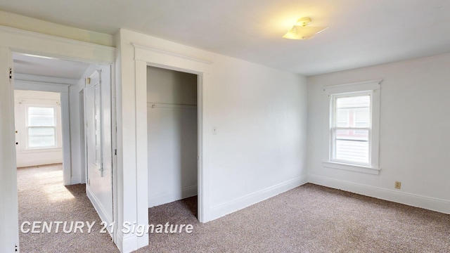 unfurnished bedroom with multiple windows, a closet, and carpet flooring