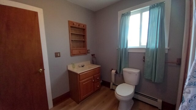 2540 S Dreyer Rd, Au Gres, MI 48703 - full bathroom with a baseboard heating unit, vanity, toilet, and wood finished floors