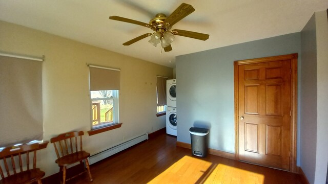 2540 S Dreyer Rd, Au Gres, MI 48703 - bedroom featuring stacked washer and clothes dryer, baseboard heating, wood finished floors, and ceiling fan