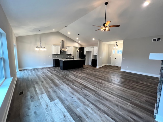 unfurnished living room featuring dark wood-style floors, visible vents, high vaulted ceiling, and ceiling fan with notable chandelier