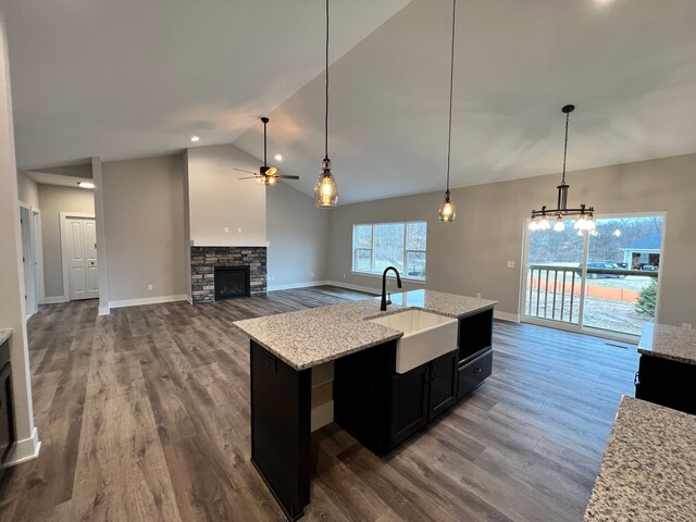 kitchen featuring dark wood-style floors, a fireplace, a ceiling fan, a sink, and dark cabinets