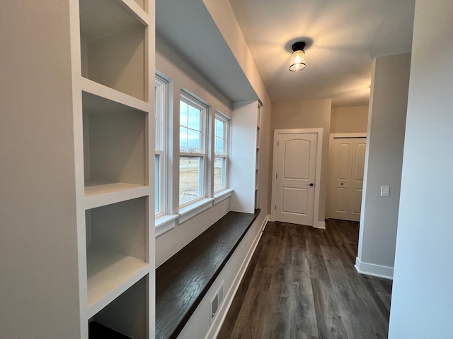 hall with dark wood-style flooring, visible vents, and baseboards