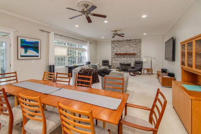 carpeted dining area featuring ceiling fan, a stone fireplace, and ornamental molding