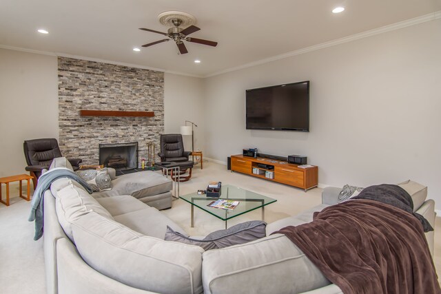 living room with carpet, ceiling fan, a stone fireplace, and crown molding