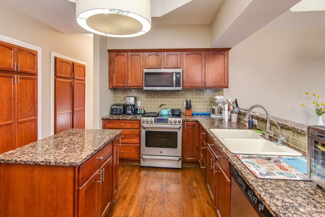 kitchen featuring backsplash, sink, hardwood / wood-style flooring, appliances with stainless steel finishes, and stone countertops