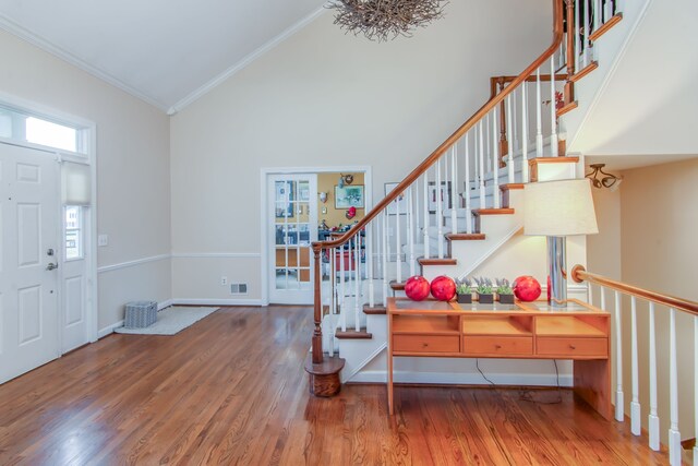 entrance foyer featuring high vaulted ceiling, wood-type flooring, and ornamental molding