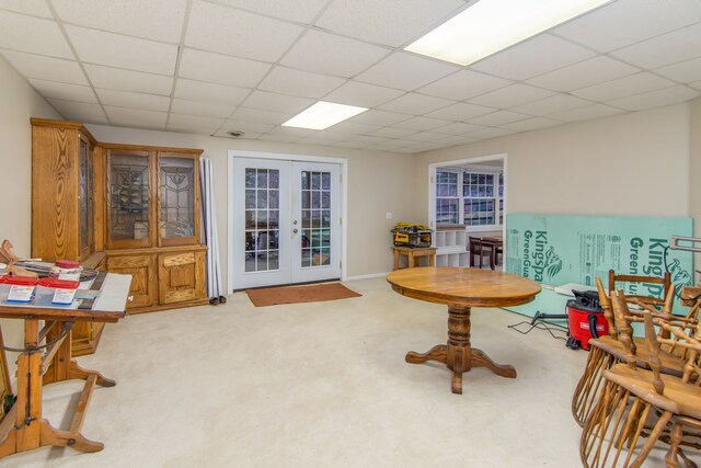 living area featuring french doors, light colored carpet, and a drop ceiling