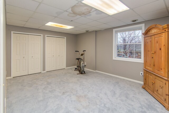 workout area with a paneled ceiling and light carpet