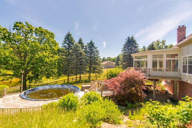 view of yard featuring a sunroom and a wooden deck