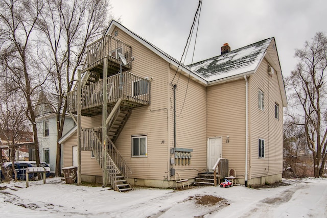 snow covered back of property featuring a balcony