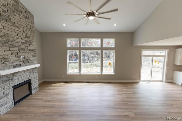 unfurnished living room with light wood-type flooring, a large fireplace, and lofted ceiling