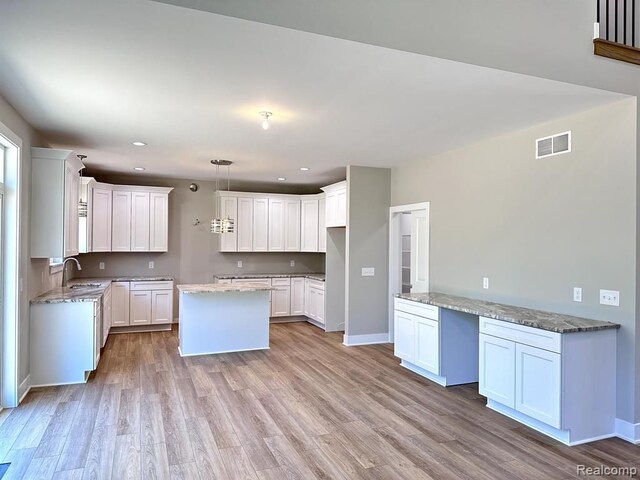 02 Textile, Saline, MI 48176 - kitchen featuring a center island, a sink, light wood-style flooring, light stone countertops, and recessed lighting