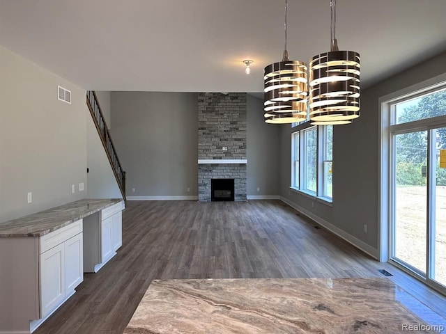 02 Textile, Saline, MI 48176 - unfurnished living room featuring dark wood-type flooring, a chandelier, a large fireplace, and baseboards